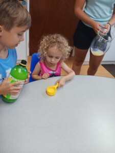 two children mixing lemon and lime ingredients for a refresher drink, two campers assisting each other at Brookeside Montessori School in Bechtelsville, PA